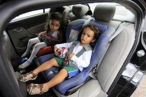 Two best friend kids sitting on their convertible car seat while talking to each other inside the car. 