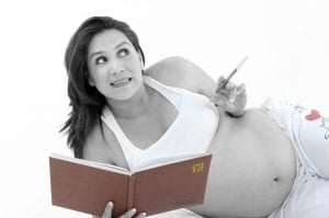 Photo of a pregnant woman lying on her side while holding a book