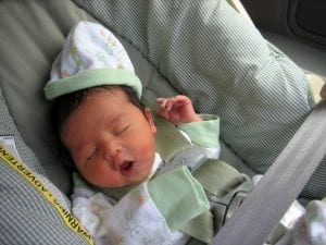 A cute sleeping baby tucked safely in an infant car seat.