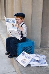 A kid reading news paper.