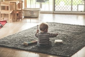 A baby plays inside the living room with best humidifier for infants. 