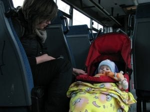 The child is sleeping in her carrier while riding the bus with her mother