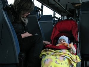 The child is sleeping in her stroller while riding the bus with her mother