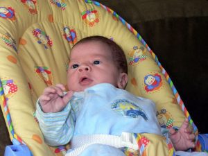 A child enjoying his baby bouncer. This yellow baby bouncer is supported with a sturdy frame.