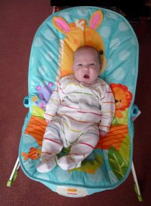 A baby enjoys his colorful baby bouncer.