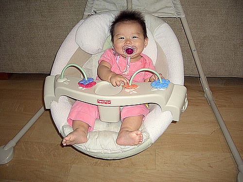 An infant in a baby swing.