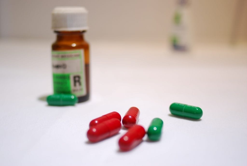 A photo of a pill bottle and red and green-colored pills