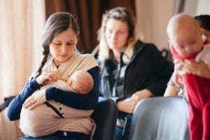 A woman breastfeeding her baby with a nipple shield. A woman and another baby is also in the picture.