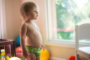 Great diaper, hypoallergenic diaper, best diapers - Innocence encapsulated, a cherubic baby, clad in a snug diaper, gazes curiously at the world beyond the window. This baby does not have any clothes on but only the best diaper or top green diaper.