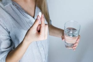 Woman taking her multivitamin tablet. Check out Maxi Health for wide variety of vitamins for teens, adults and even pregnant women for baby care