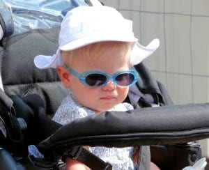 A cute baby girl wearing a hat and a shade in an Britax B Agile stroller