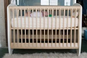 A baby sleeping on its crib mattress.