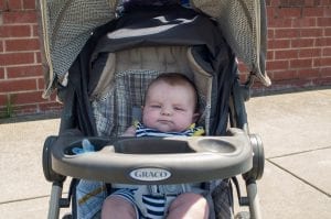 A baby boy silently sitting on his stroller