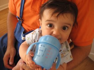 toddler drinking from his blue sippy cup