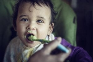 A mother feeding her child with baby food.