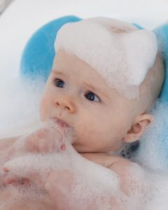 Shampoo for kids: Baby with foam on head from the best kids' shampoo and conditioner, gazing thoughtfully.