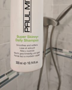 Shampoo for kids: Bottle of Paul Mitchell's best Super Skinny Daily Shampoo in a shower, designed to smooth & soften hair.