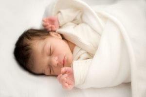 A newborn wrapped in a cozy blanket, sleeping peacefully, perhaps with the aid of one of the best white noise applications.