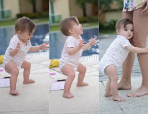 A happy baby learning how to walk by the pool.