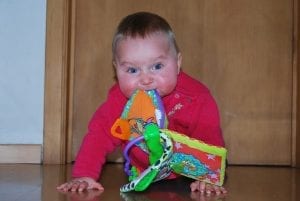 A cute baby with expressive eyes nibbling his toys.