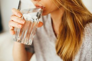 Girl staying hydrated and drinking water from a glass 