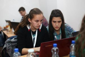 Two students focused on doing school activities in their laptop with water bottle in front