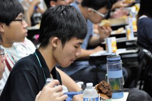 A male student having a snack and bottle while listening to an ongoing lecture