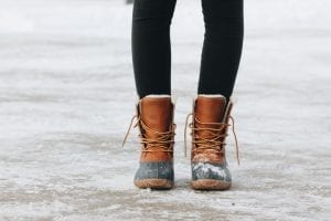 An important feature of winter boots is being waterproof and will keep the feet warm. A pair of feet wearing the greatest boots while outside during a cold winter season.