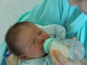 A mother feeding the baby with best formula through a feeding bottle.