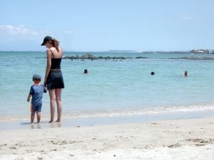 Mom playing in the beach with her toddler.