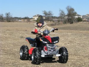 A young adventurer riding the thrilling Fisher-Price Toy Cool Kawasaki KFX, a realistic-looking off-road vehicle that provides an exciting and safe driving experience, inspiring little drivers to confidently explore their surroundings and enjoy endless hours of outdoor fun