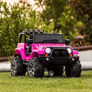 Power Wheels: A pink and black Power Wheels Jeep is positioned on the grass, showcasing its bright headlights and additional roof-mounted lights.