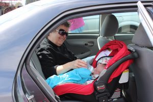 The infant is using Britax car seat. The father is making sure that the baby is comfortable with the vehicle seat. 