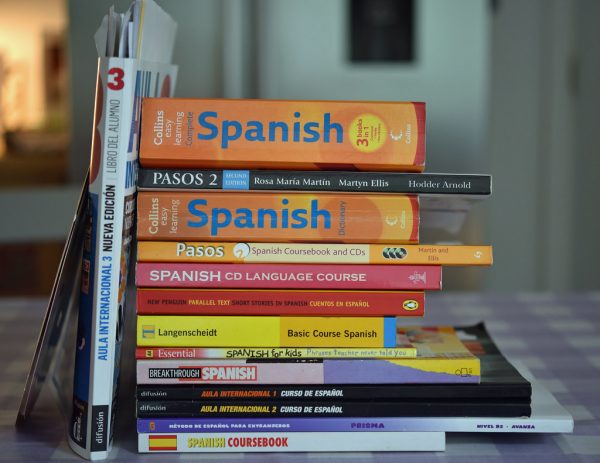 A stack of various Spanish language learning books and course materials on a table, showcasing different authors and publishers.