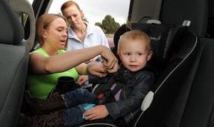 A mom with her friend make sure that the installation of infant car seat is secure. 