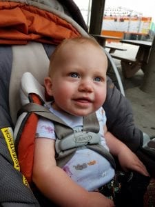 An adorable baby sits comfortably in a plush car seat, secured with straps and surrounded by safety padding. Their bright eyes gaze curiously at the world outside, reflecting wonder and innocence. The soft fabric of the car seat provides gentle support, ensuring a cozy, secure ride for the little traveler.