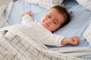 Sound machine for baby: A baby, nestled in a soft bed, fast asleep and gently breathing.