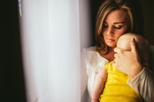 A postpartum mom holding her baby tight.