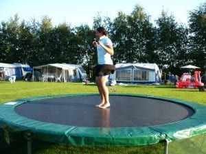 renting a trampoline or buying a trampoline? Trampolines are the best thing to have especially for kids. This is an image of a kid jumping on a green trampoline.