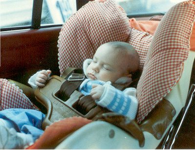 An infant peacefully sleeping on a carseat. 