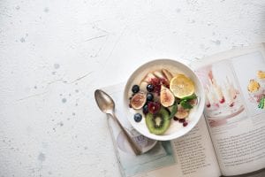A cookbook and a bowl of salad on the table