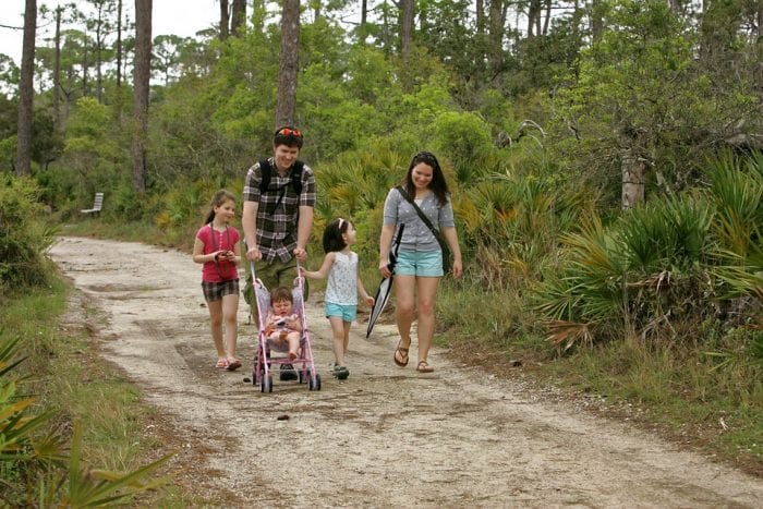 A family walking on a rough road with their little one in a terrain stroller. It is ideal for families with an active lifestyle.