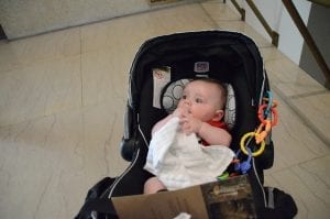Best Car Seat Stroller Combo: A baby is sitting in a stroller, which is part of the car seat combos, gazing curiously at the camera, illustrating a best-in-class design for infant travel systems.