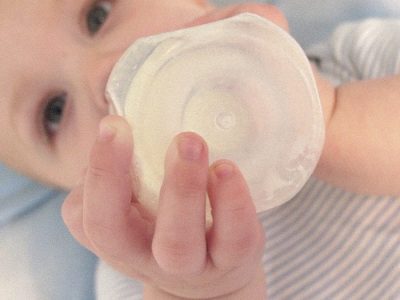 A baby drinking milk with an Iron supplement formula.