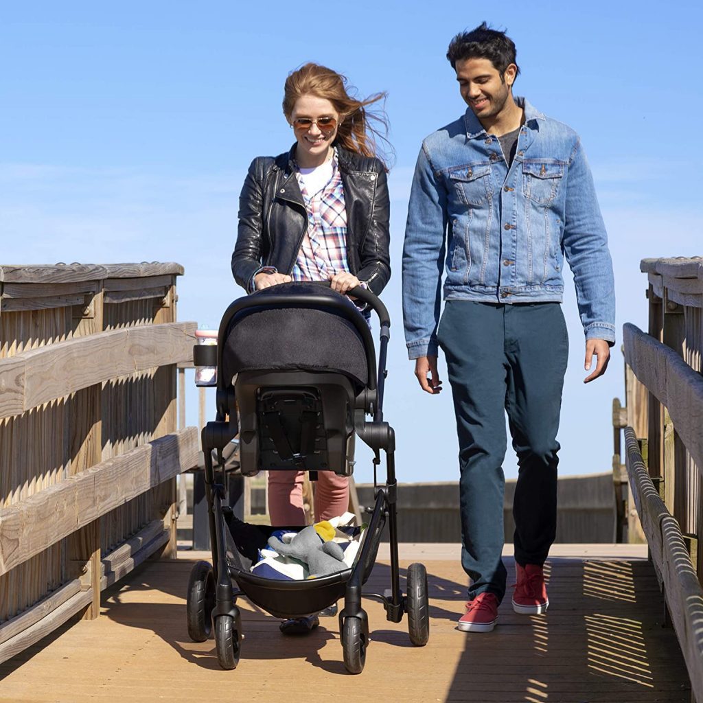 Parents leisurely strolling along a park pathway, pushing their baby in a comfortable stroller