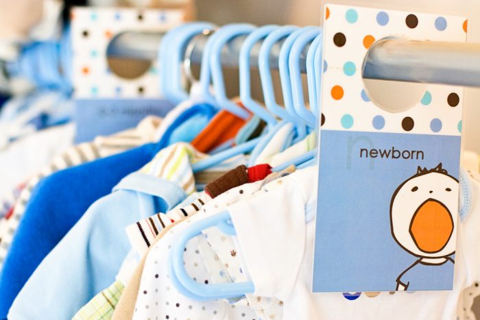 Blue plastic hangers with different newborn baby's clothes 