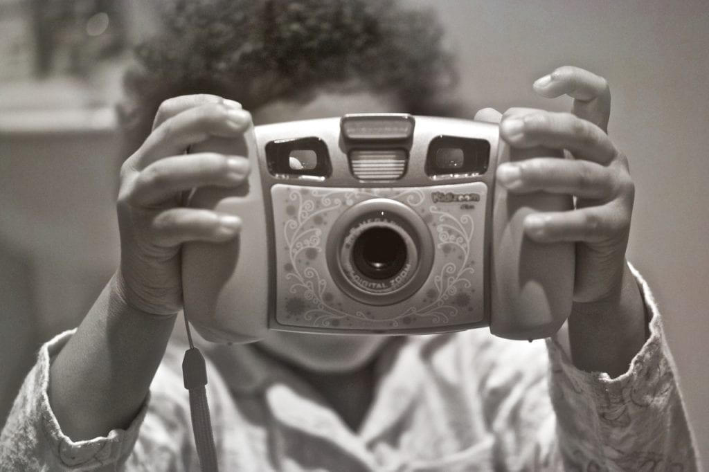 A kid holds a Kidizoom spin and smile camera. 