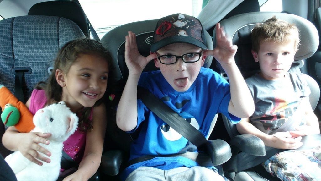 Three children sitting inside the car