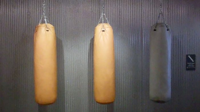 Gray boxing bag hangs beside the orange bag. 