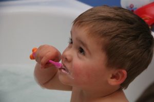 Baby joyfully holding a pink baby toothbrush. He brushes his teeth with that toothbrush for a delightful start to the day.